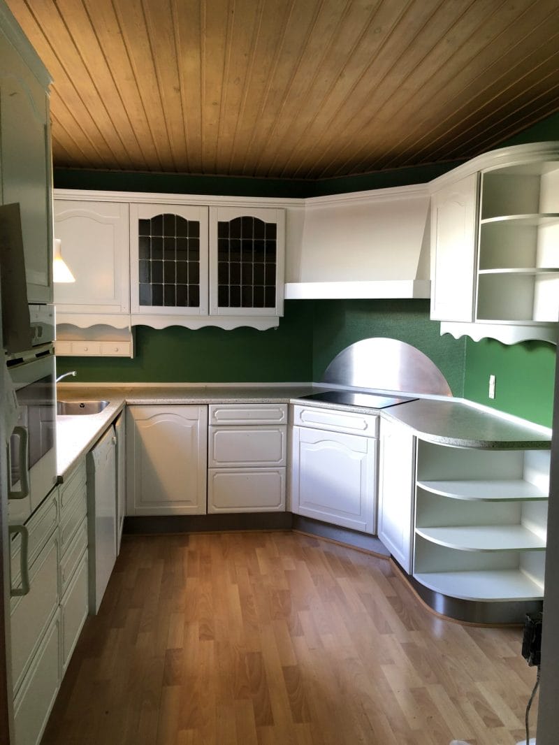 Køkken med hvide skabe og grønne vægge