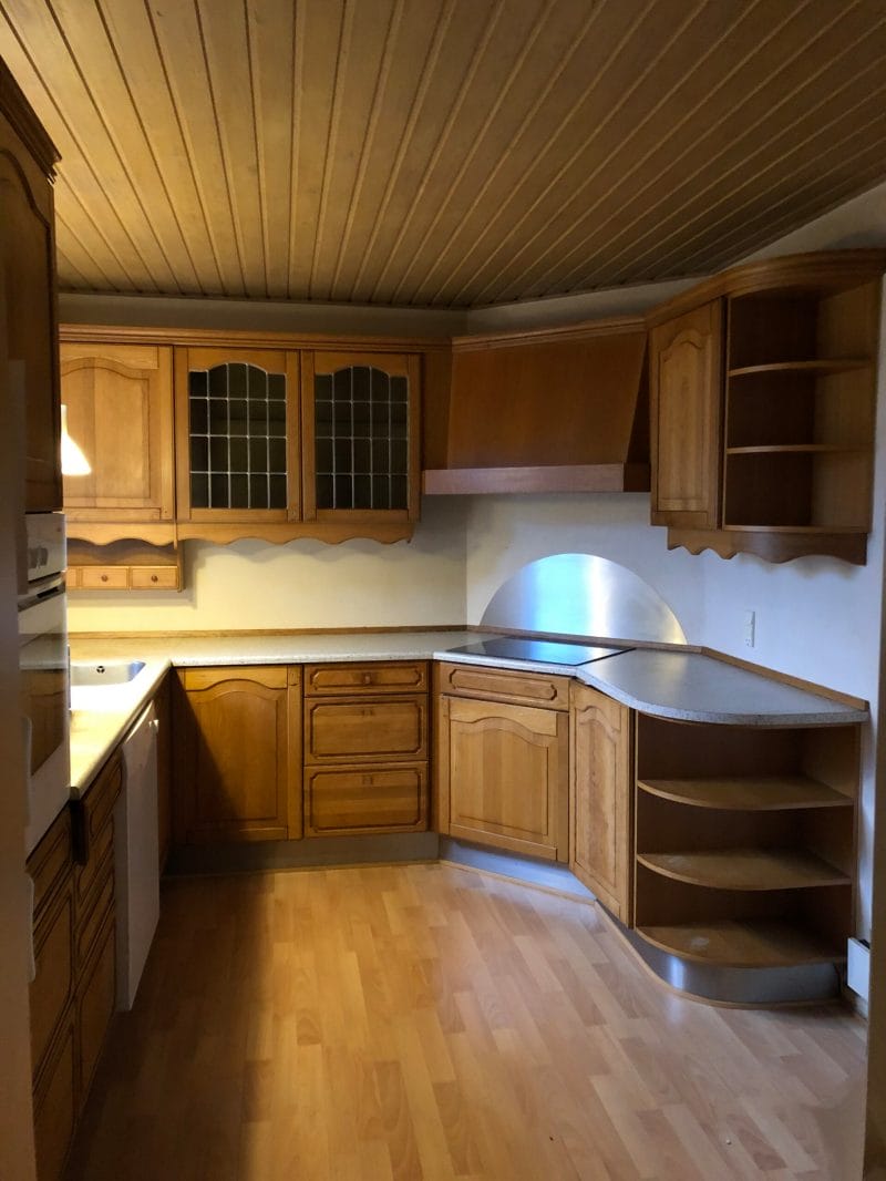 Køkken med lyse træskabe og laminatbordplade