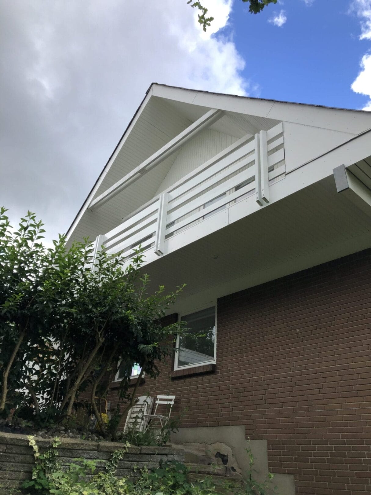 Murstenshus med hvid altan og blå himmel