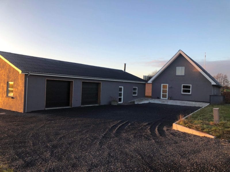 Gråt hus med garage og grusbelagt indkørsel