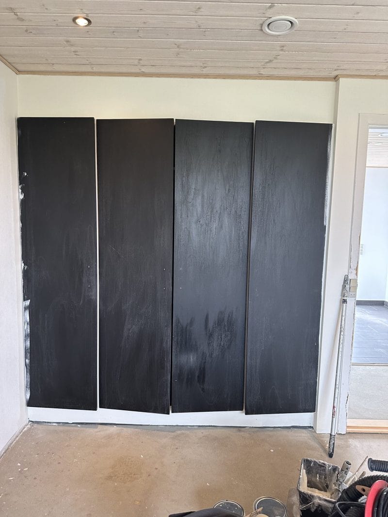 Sortmalede træpaneler monteret på hvid væg